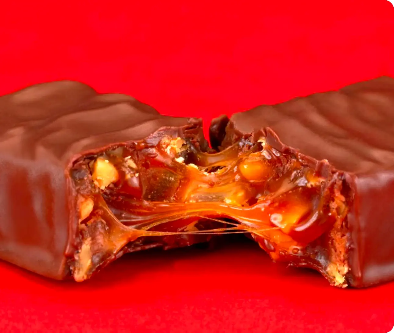 A chocolate bar pulled apart to reveal a gooey caramel and nut filling.